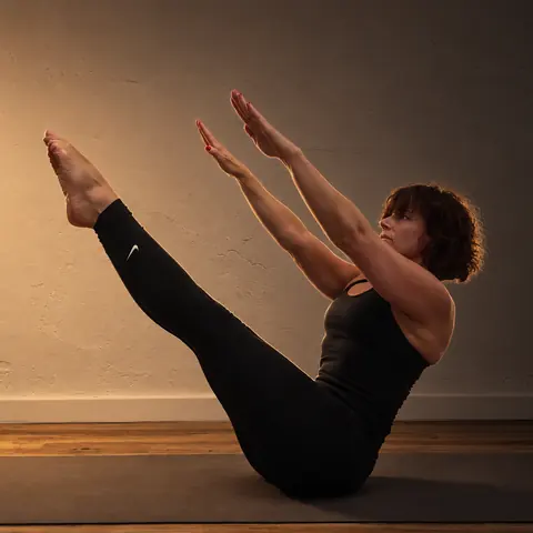 Alicia Sanz en una postura de Pilates sobre la colchoneta, con las piernas y los brazos extendidos en V